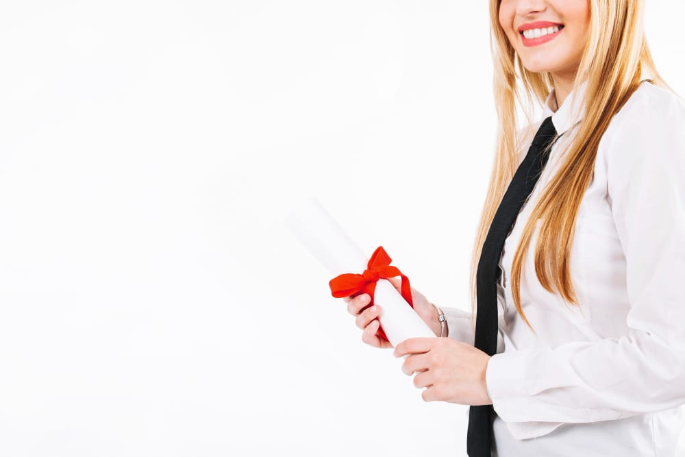 jeune femme blonde tenant un diplome avec un ruban rouge dans les mains